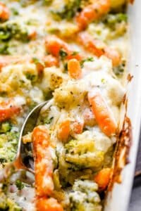 overhead close up shot of cooked broccoli, carrots, and cauliflower in a baking dish