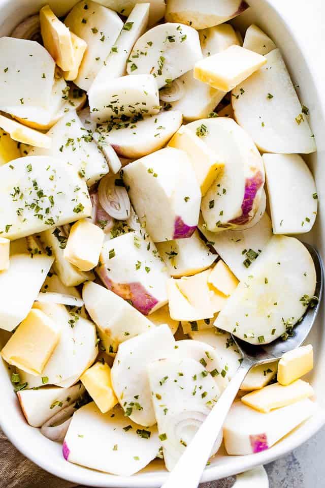 Raw sliced turnips topped with butter, herbs, and seasonings.