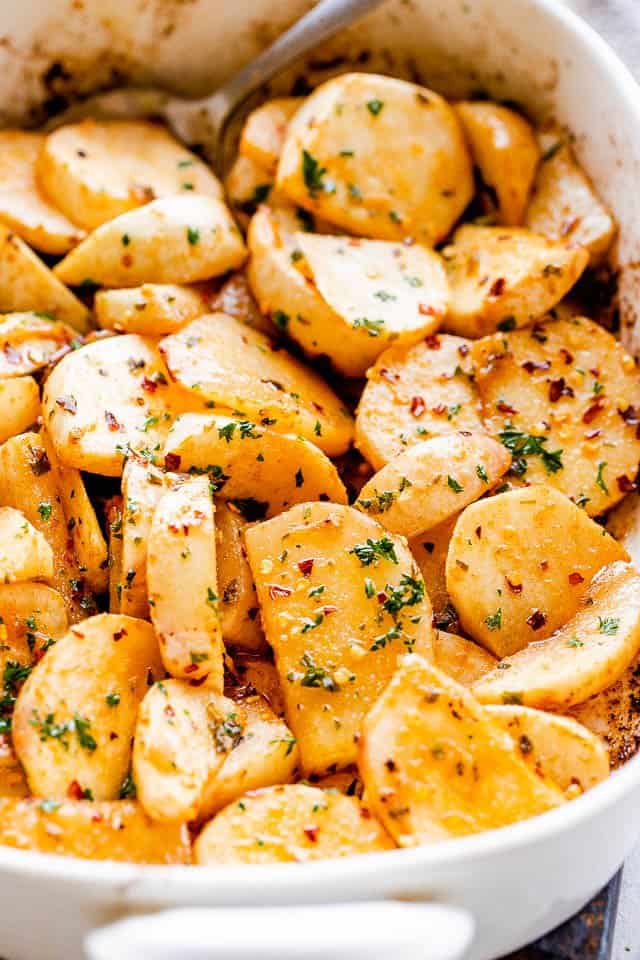 Image of a baking dish with roasted turnips topped with herbs and pepper flakes.