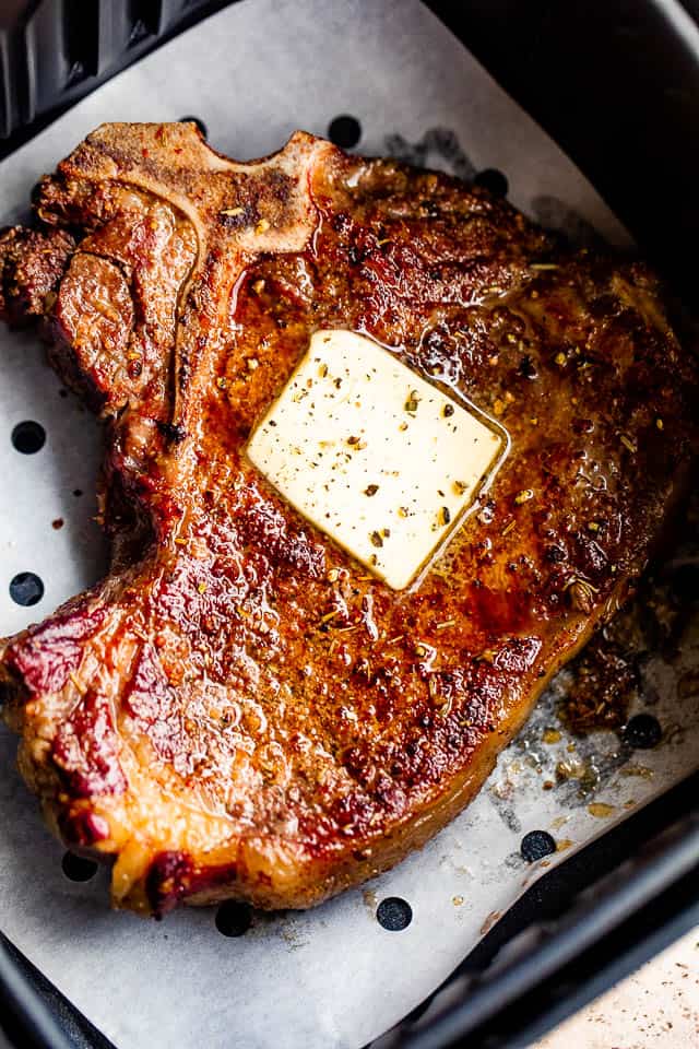 overhead shot of air fryer cooked steak topped with a pat of butter