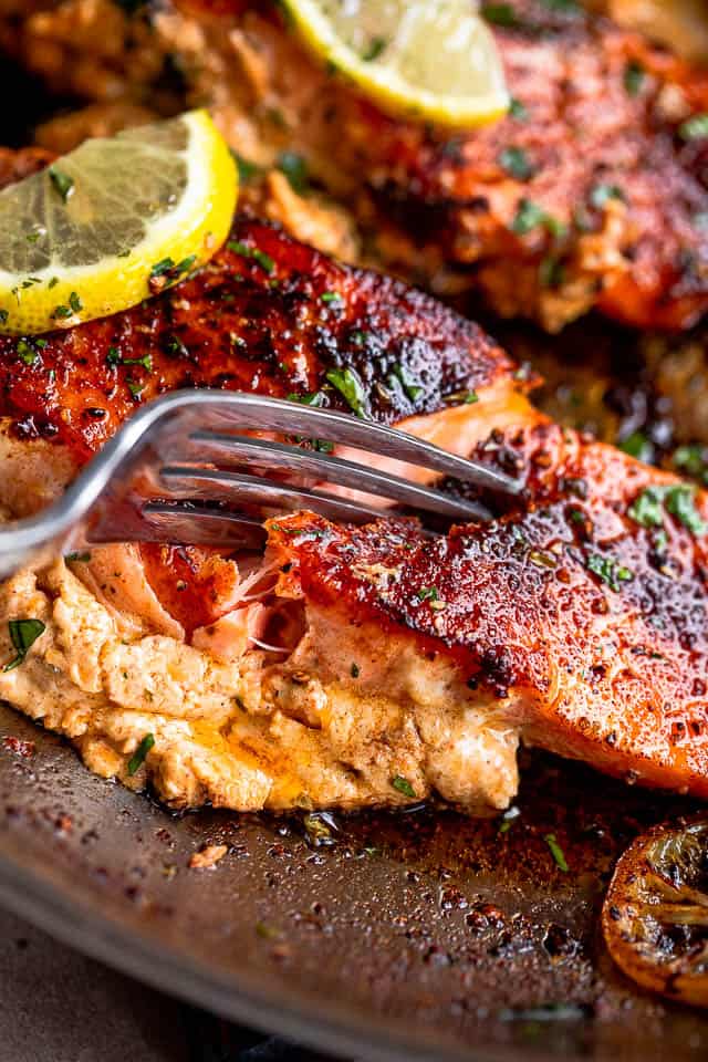 fork cutting into cooked salmon fillet stuffed with creamy cajun filling