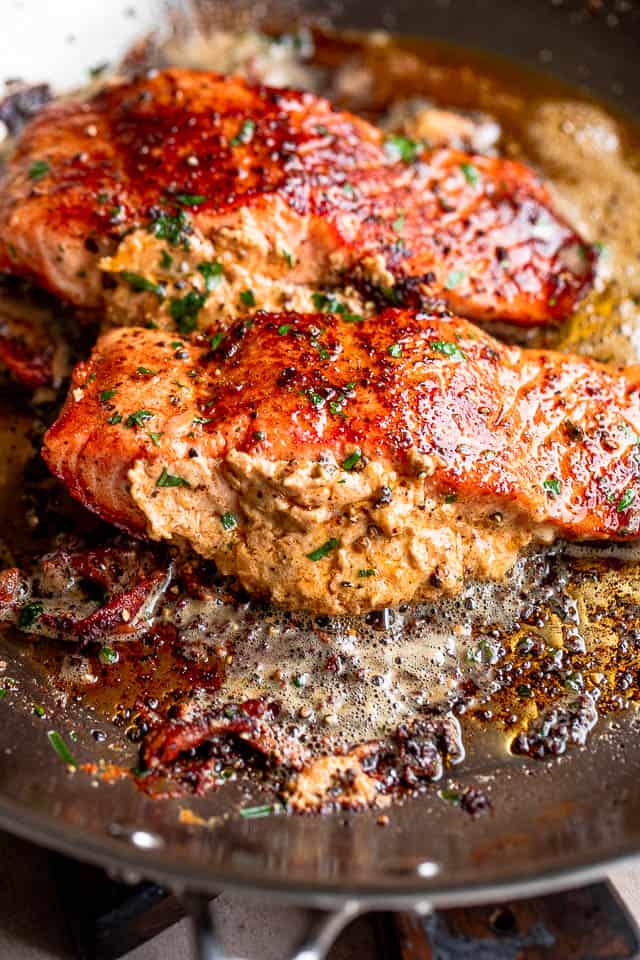 two stuffed salmon fillets cooking in a skillet