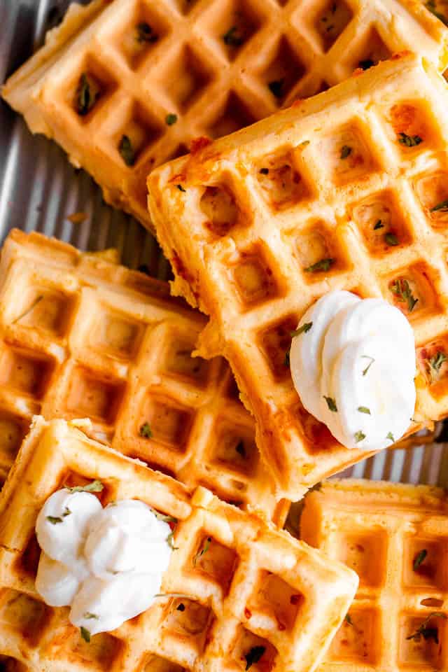 close up overhead shot of chaffles placed on a baking sheet and topped with dollops of sour cream