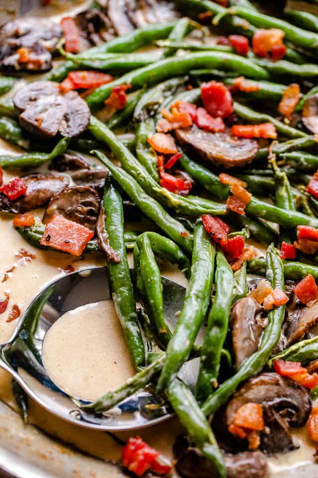green beans and mushrooms cooking in a creamy parmesan sauce and topped with diced bacon