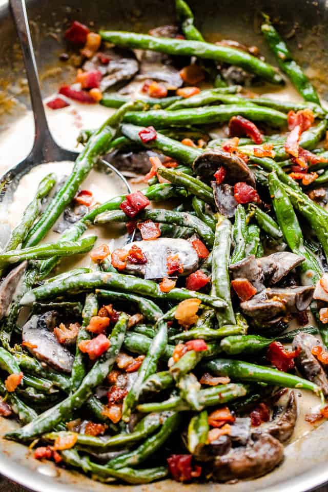 Close-up image of cooked green beans topped with bacon.