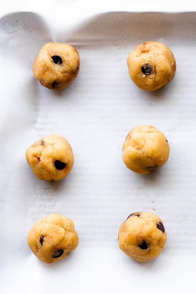 cookie dough balls on baking sheet covered with parchment paper