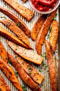 overhead shot of baked sweet potatoes served with a small bowl of ketchup