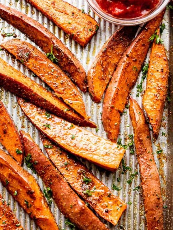 overhead shot of baked sweet potatoes served with a small bowl of ketchup