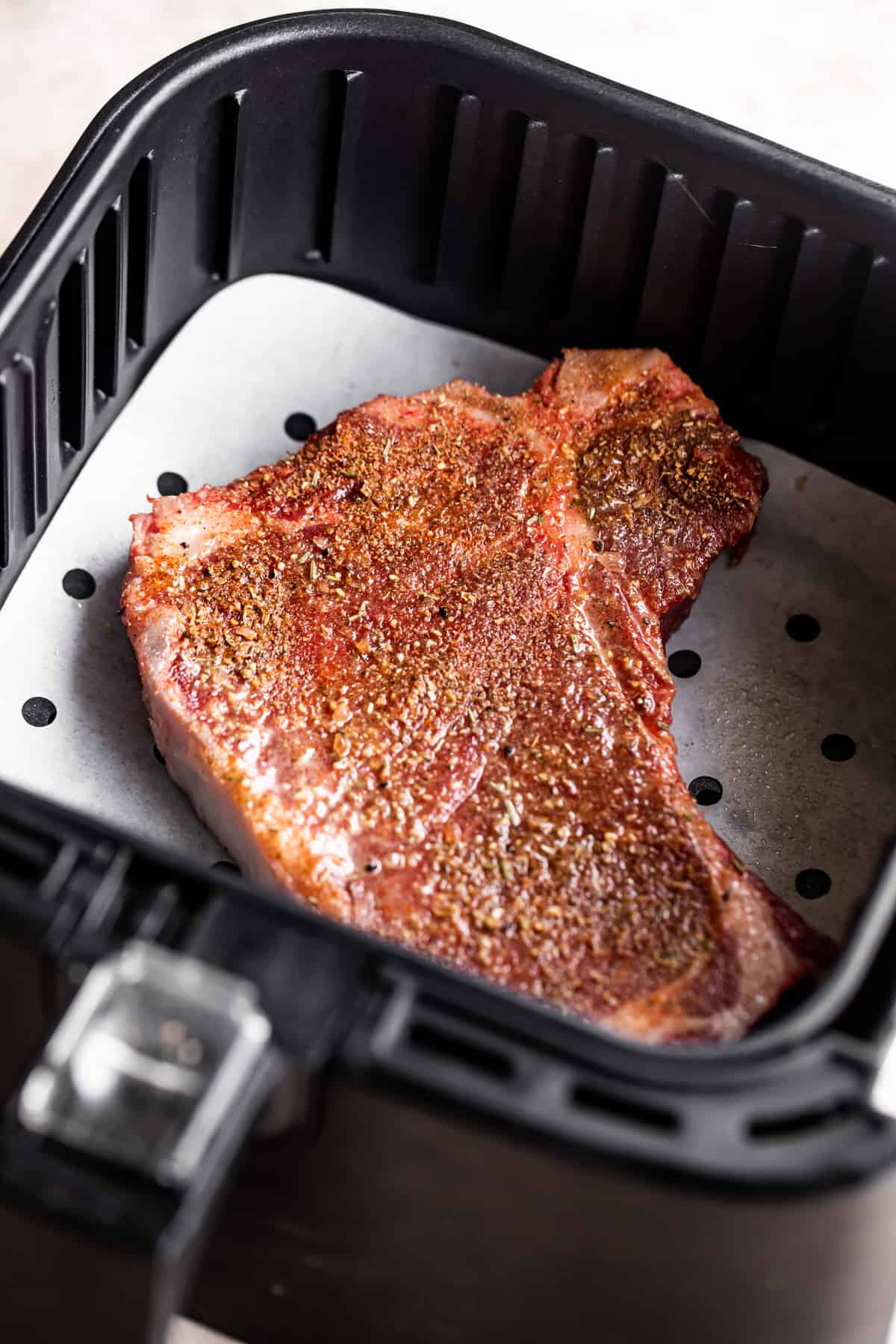 Raw steak in an air fryer basket