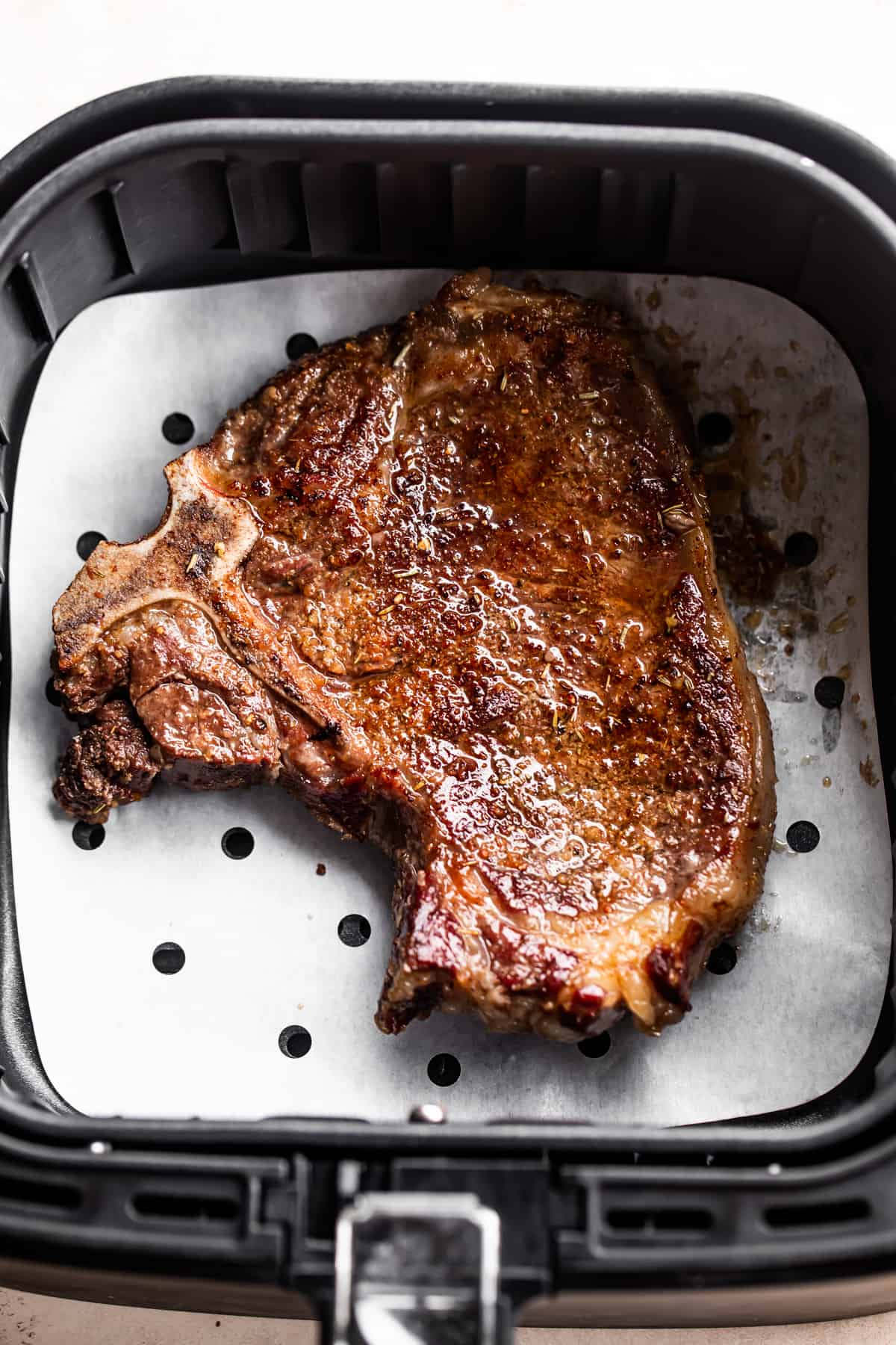 A cooked steak in an air fryer basket