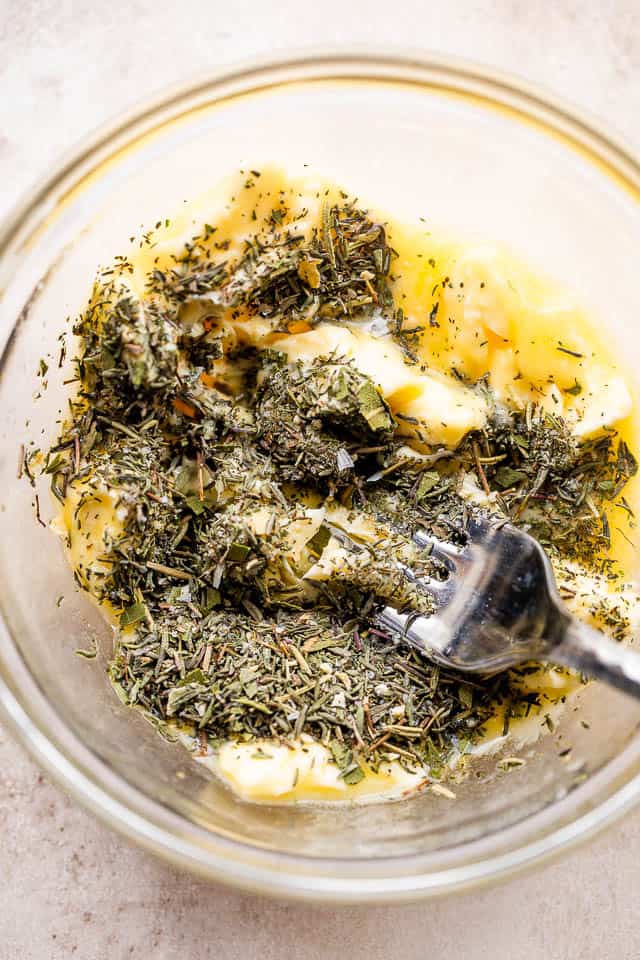mashing butter and dried herbs in a bowl