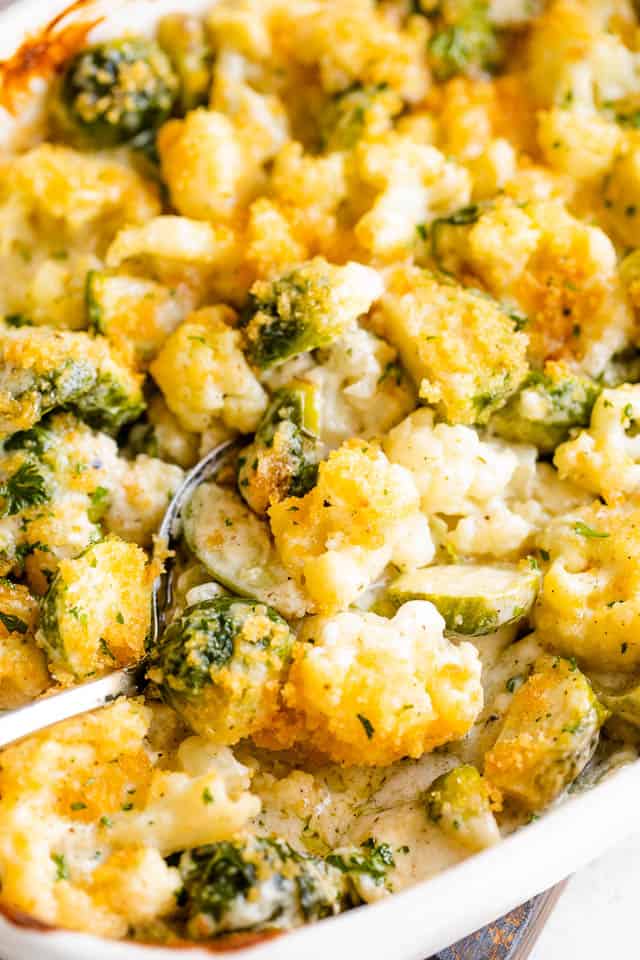 spooning out cheesy cauliflower and brussel sprouts casserole