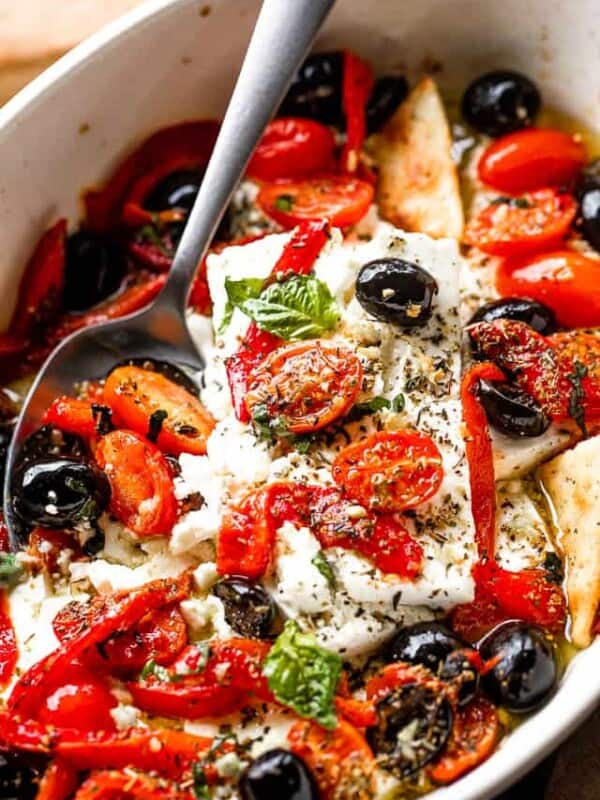 side shot of a baking dish with baked feta cheese, tomatoes, olives, and red peppers