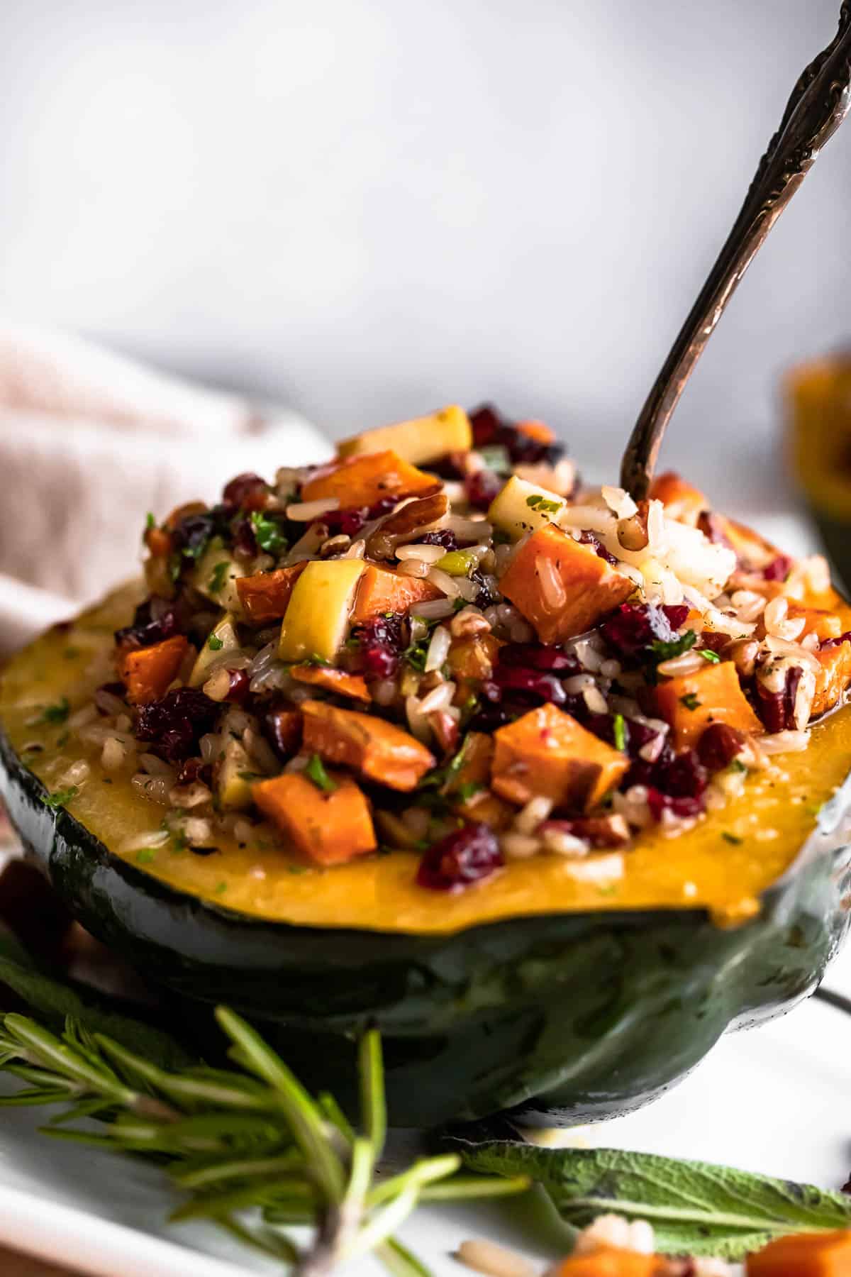 halved acorn squash stuffed with rice, berries, and butternut squash, and a fork placed on top of the stuffing.