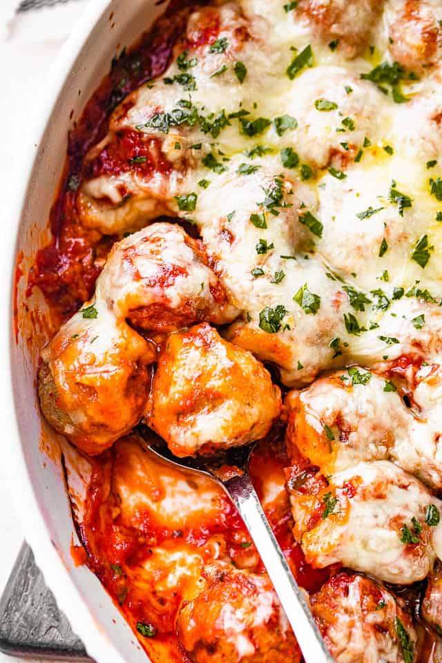 baking dish with meatballs in tomato sauce and topped with melted cheese