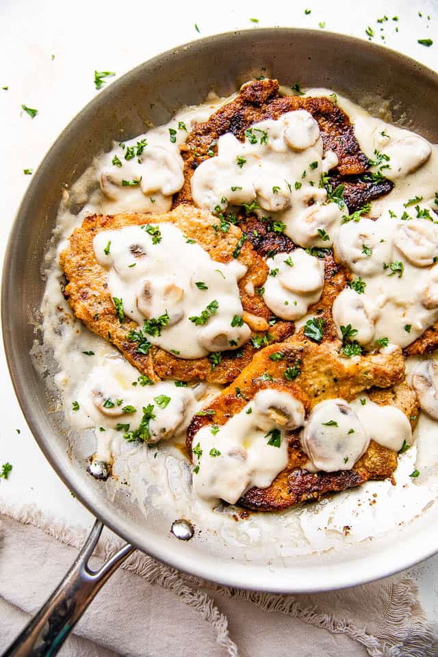 skillet with four pork chops in a creamy marsala mushroom sauce