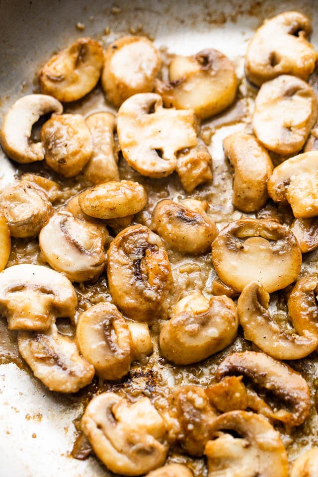 Cooking sliced mushrooms to make creamy marsala sauce.