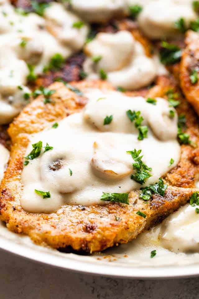 close up shot of thin fried pork chop topped with creamy marsala mushroom sauce