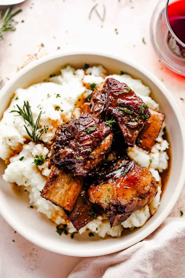 short ribs served over mashed potatoes and a glass of wine to the side