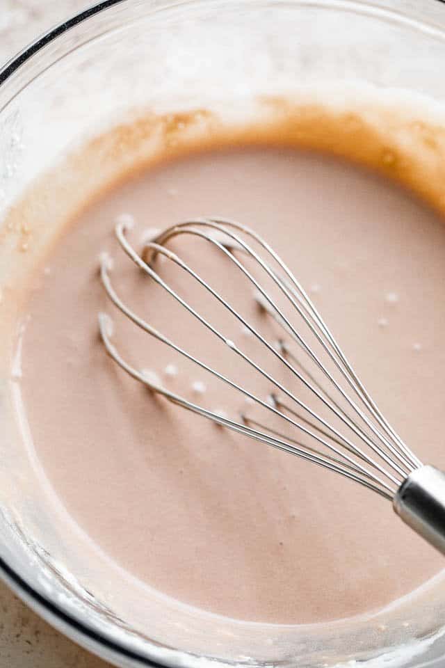 whisking cream cheese, chocolate syrup, and heavy cream in a glass bowl