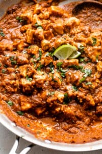 close up shot of sofritas in a skillet garnished with lime slices and cilantro