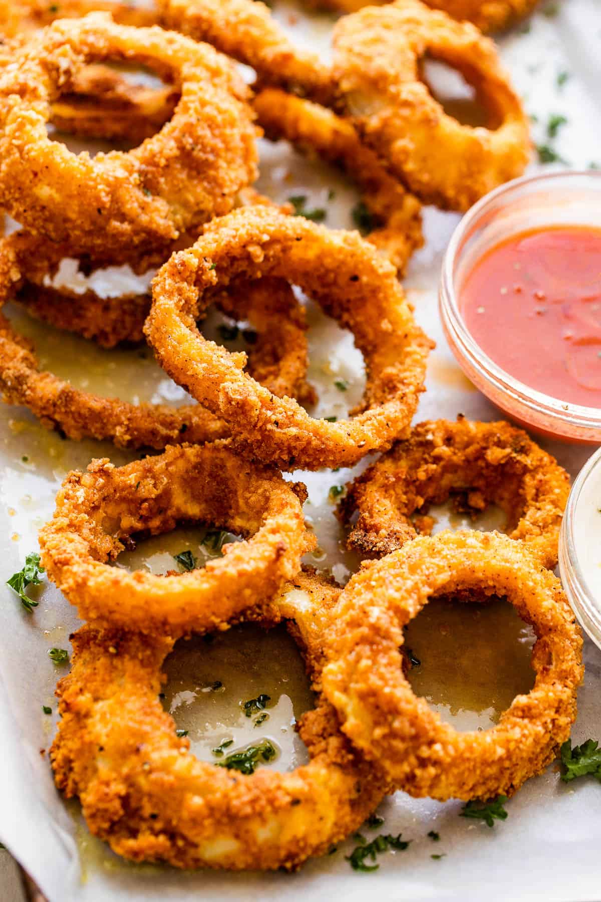photo of onion rings served on a plate with ketchup and ranch