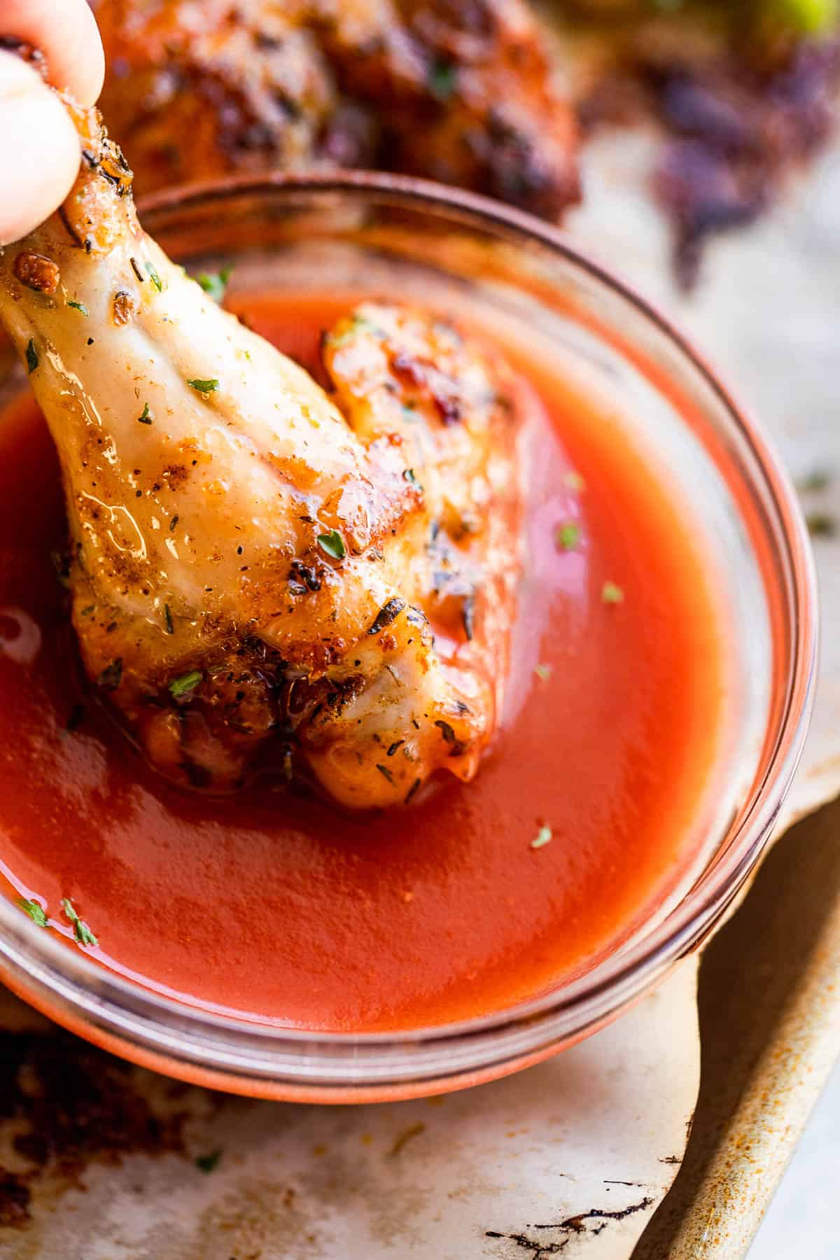 dipping chicken drumette in sriracha sauce