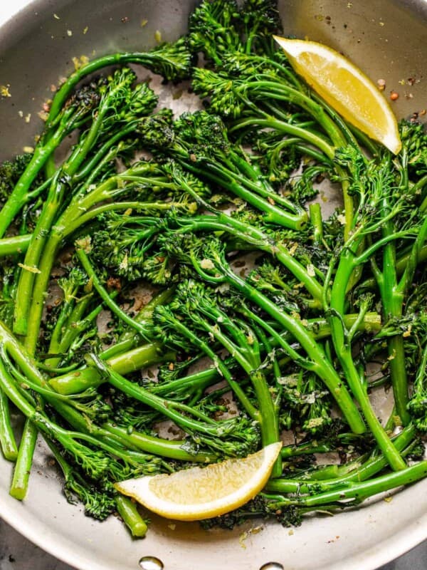 closeup shot of sauteed broccolini served with lemon wedges