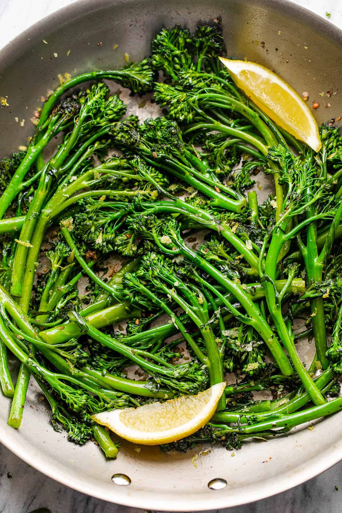 closeup shot of sauteed broccolini served with lemon wedges