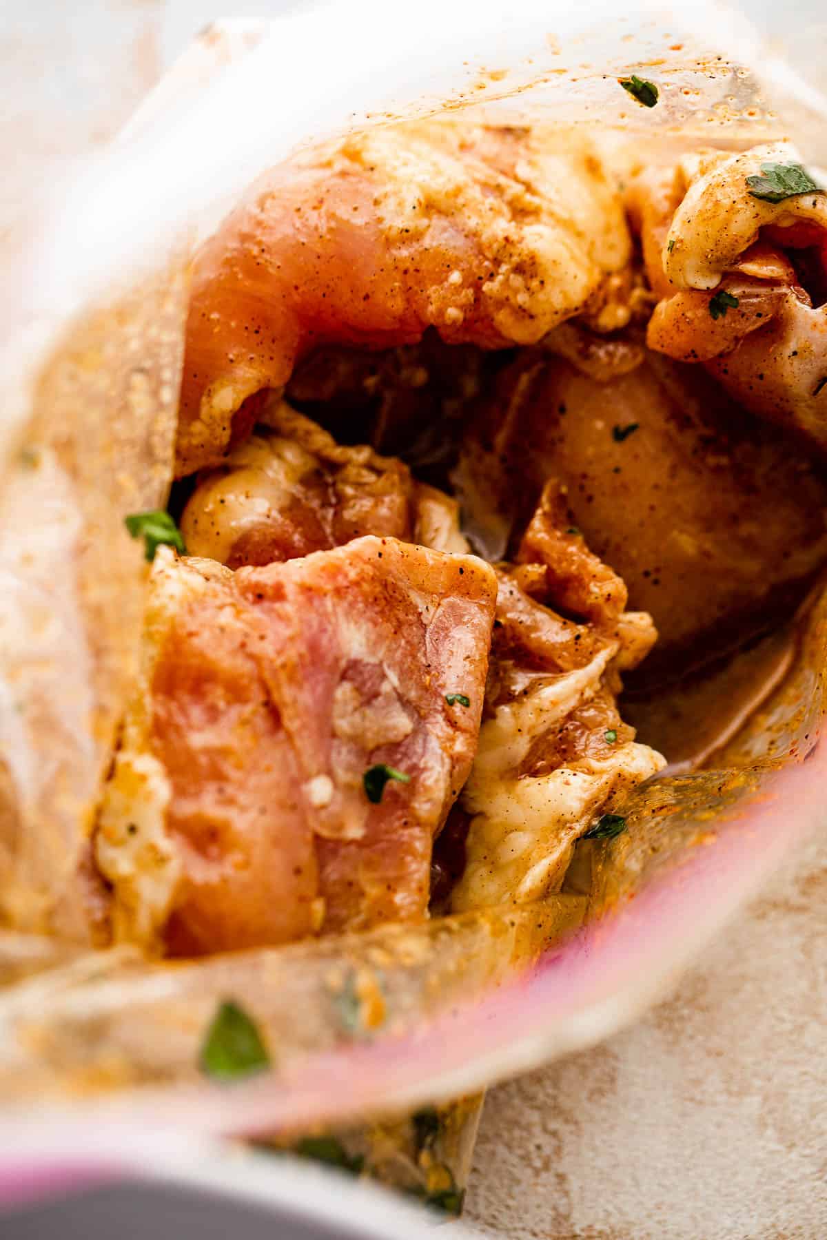 chicken thighs soaking in marinade inside ziploc bag