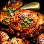 close up picture of cilantro lime chicken thighs with lime wedge next to the thighs.