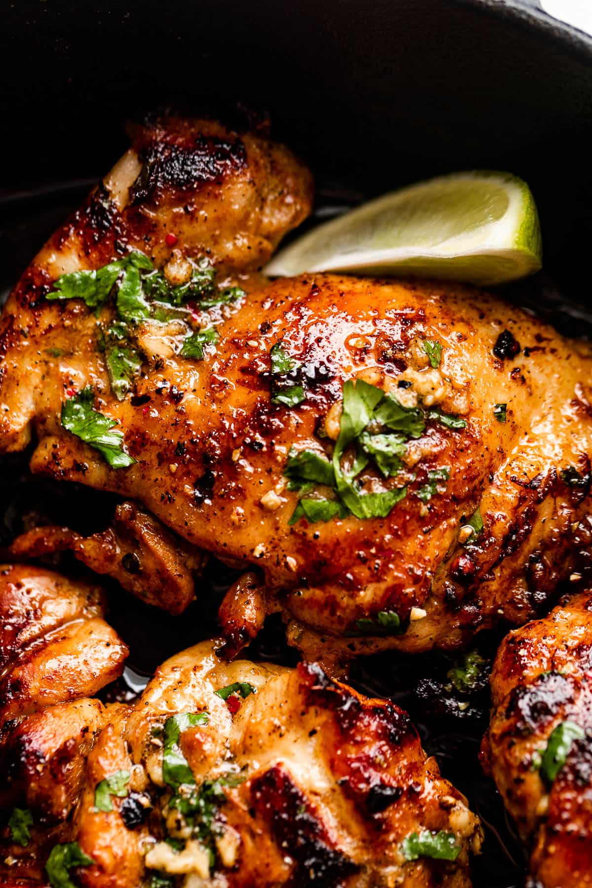 close up picture of cilantro lime chicken thighs with lime wedge next to the thighs.