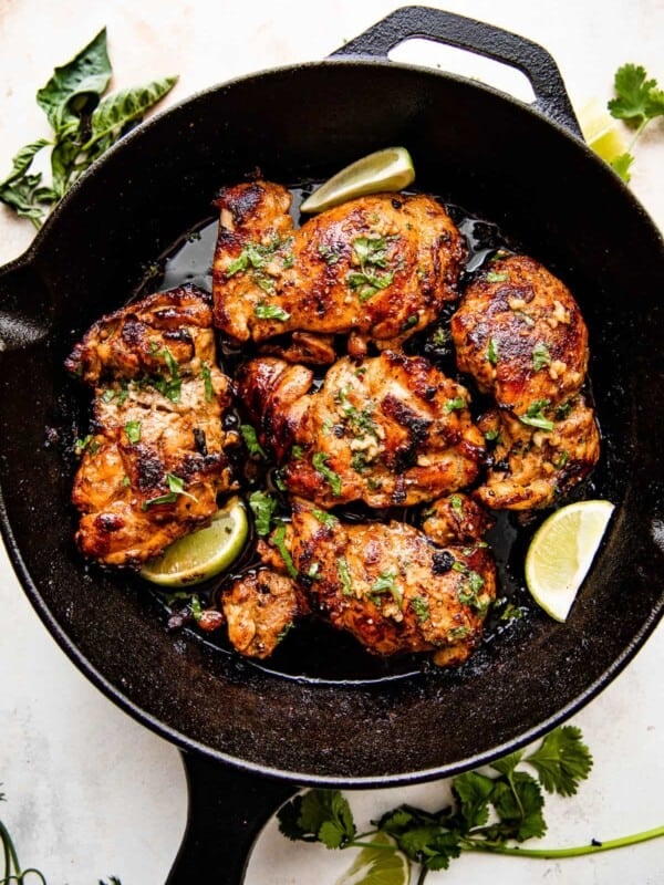 overhead picture of chicken thighs cooking in a cast iron skillet