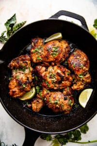 overhead picture of chicken thighs cooking in a cast iron skillet