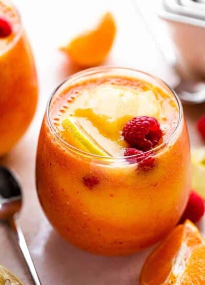 mango berry smoothie in a drinking glass garnished with raspberries