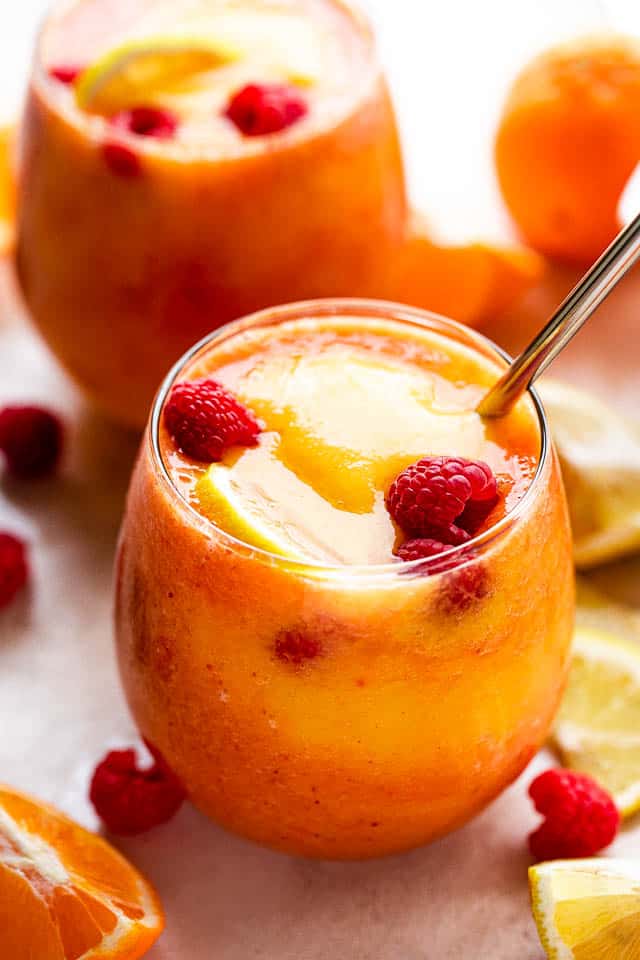 mango berry smoothie in a drinking glass garnished with raspberries