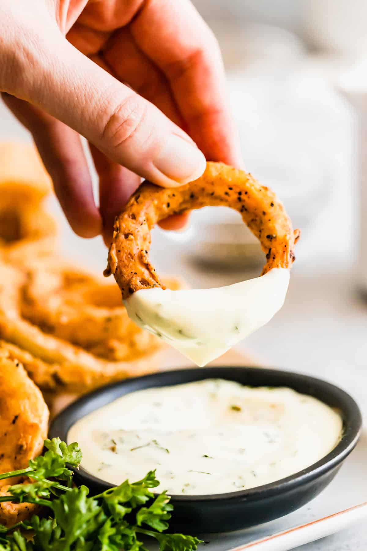 Dipping an onion ring in ranch.