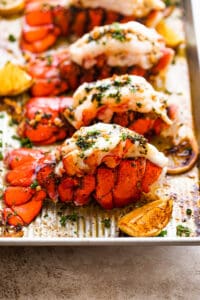 side shot of cooked lobster tails on a baking sheet.