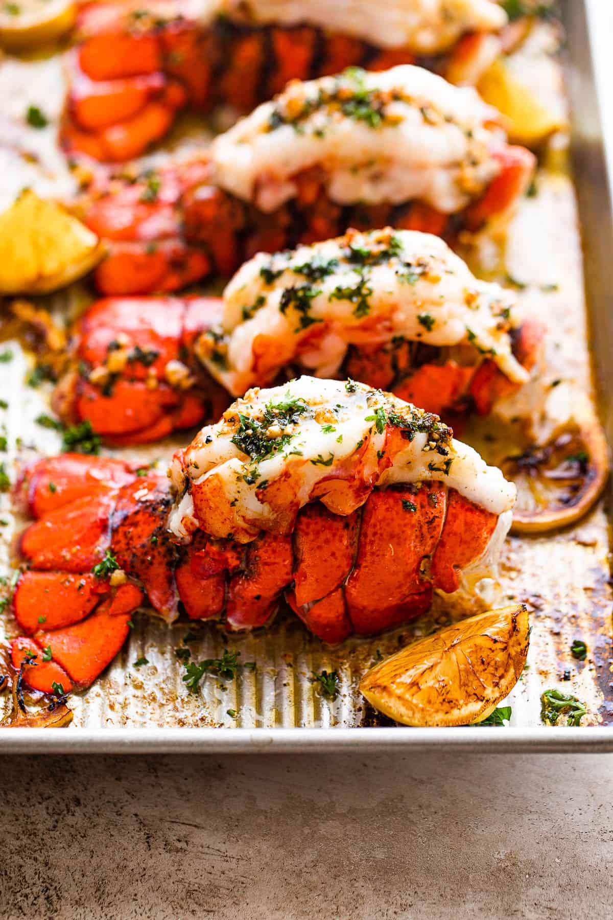 Four Cooked Lobster Tails Lined Up on a Baking Sheet