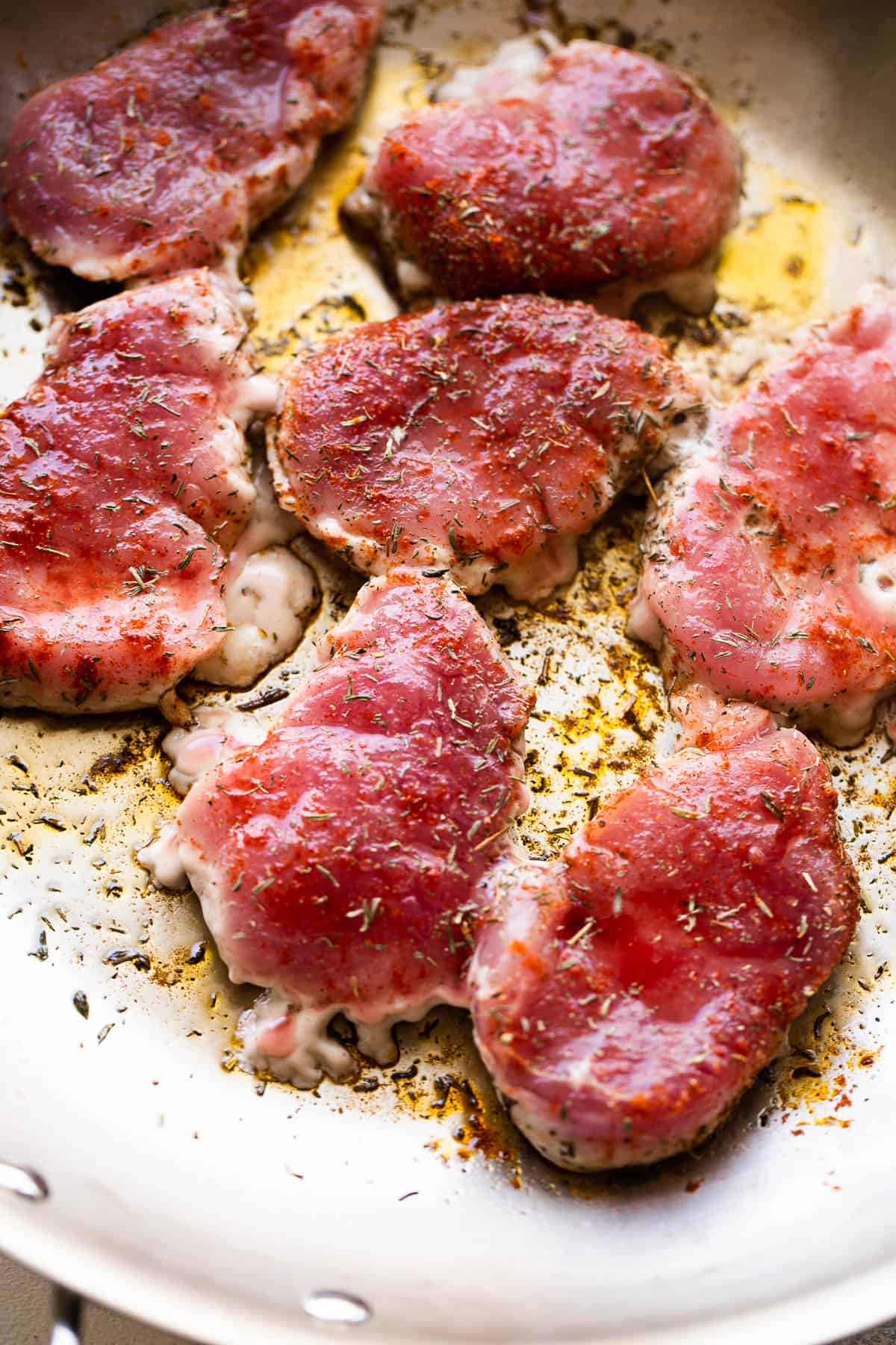 raw pork tenderloin medallions cooking in a skillet