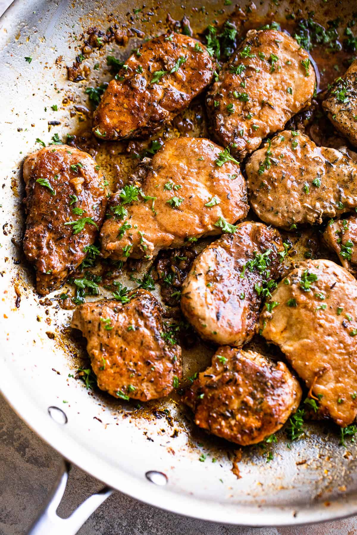 Cooking pork medallions in a stainless skillet.