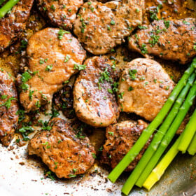 stainless skillet with pork medallions and asparagus