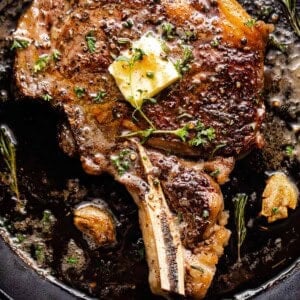 overhead shot of a ribeye steak cooking in a cast iron skillet