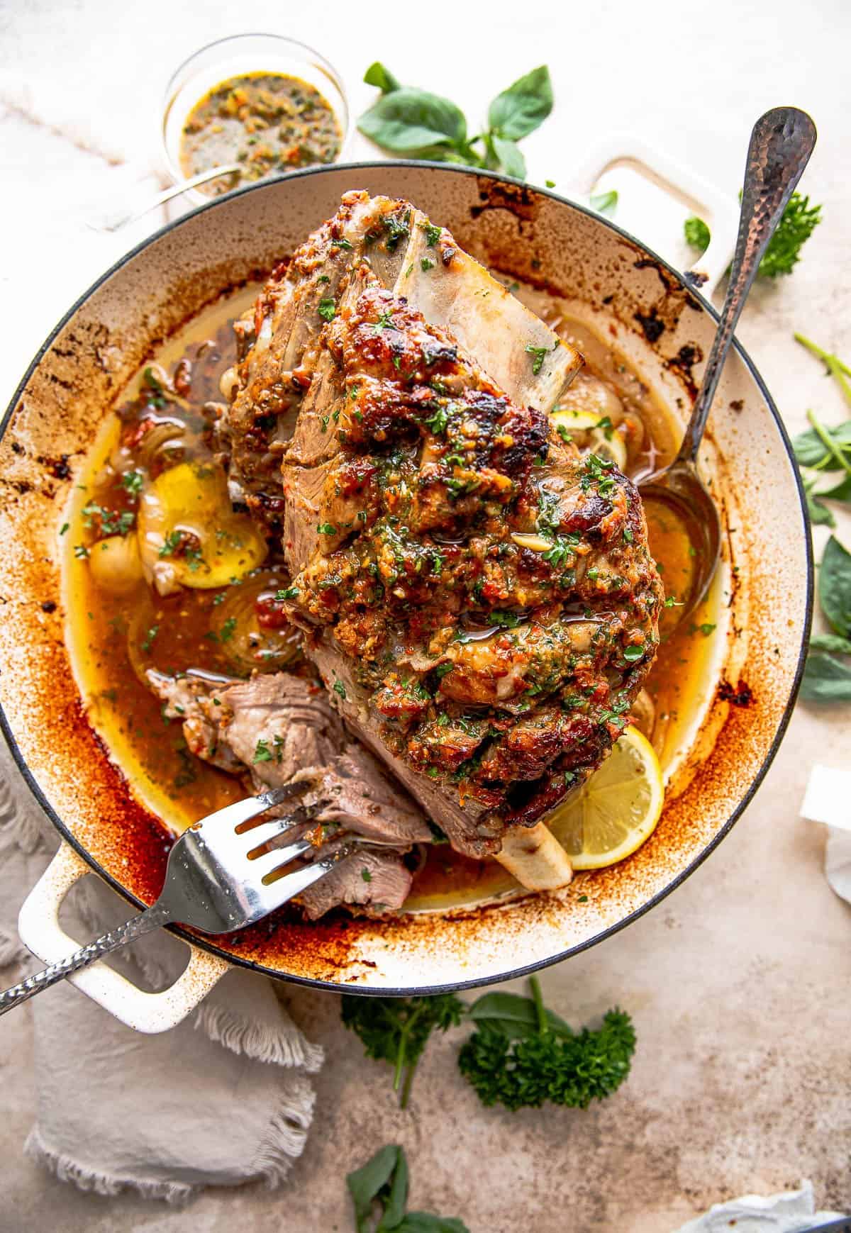 overhead shot of a cooked lamb shoulder in a white roasting pan