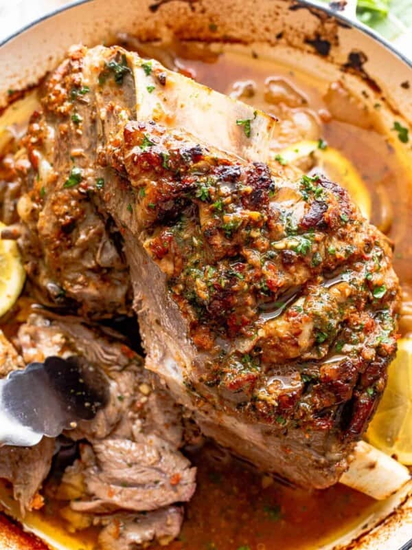cooked lamb shoulder in a white roasting pan