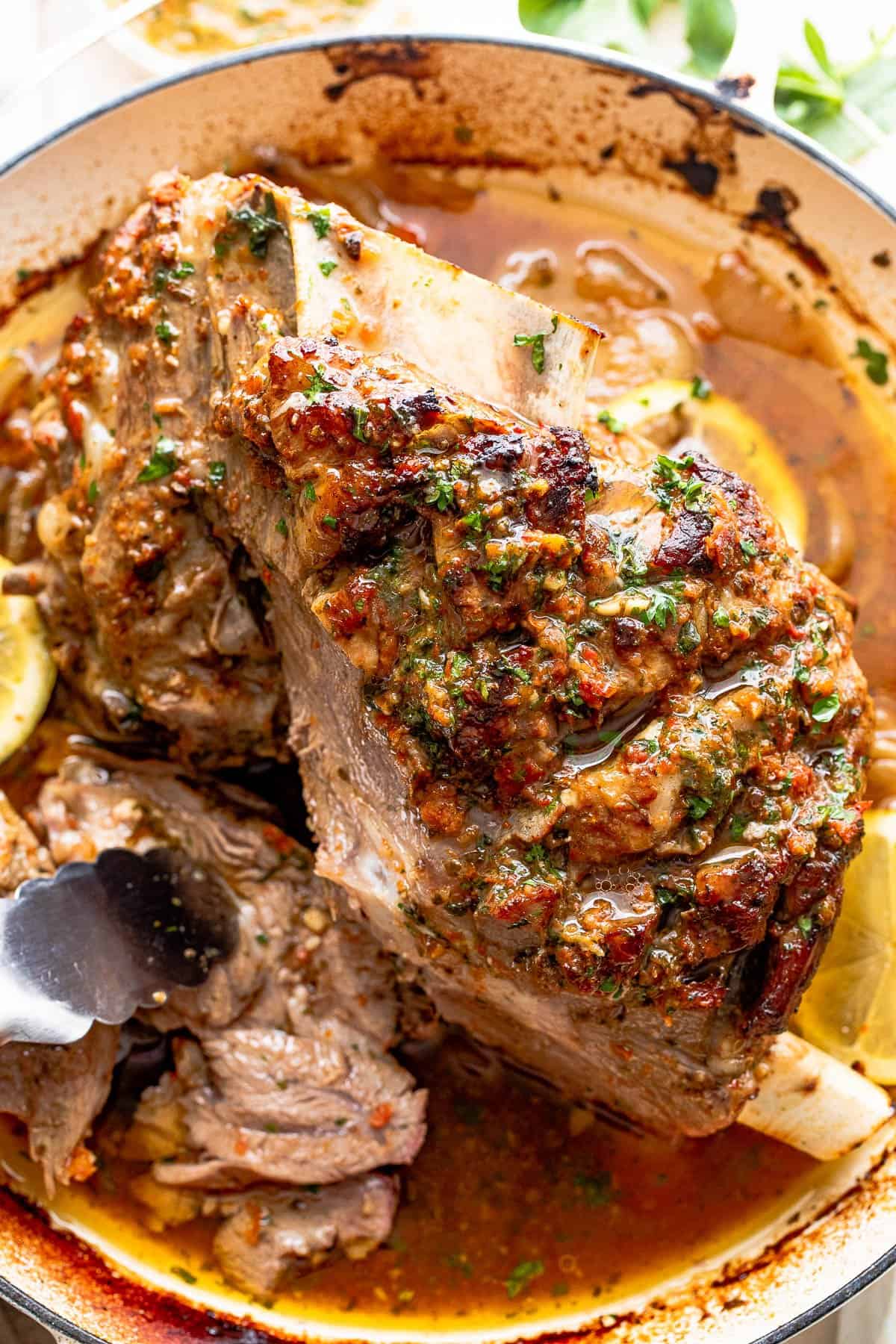 Cooked lamb shoulder in a white roasting pan.