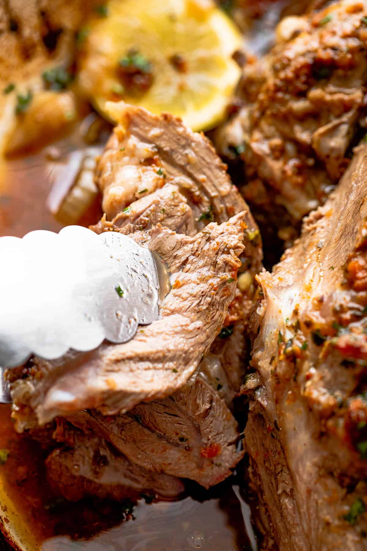 Pinching off lamb meat with stainless steel tongs.