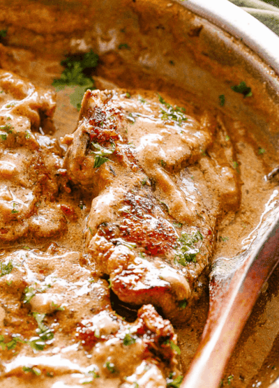 Close-up view of pan-seared pork chops with onion gravy in a skillet
