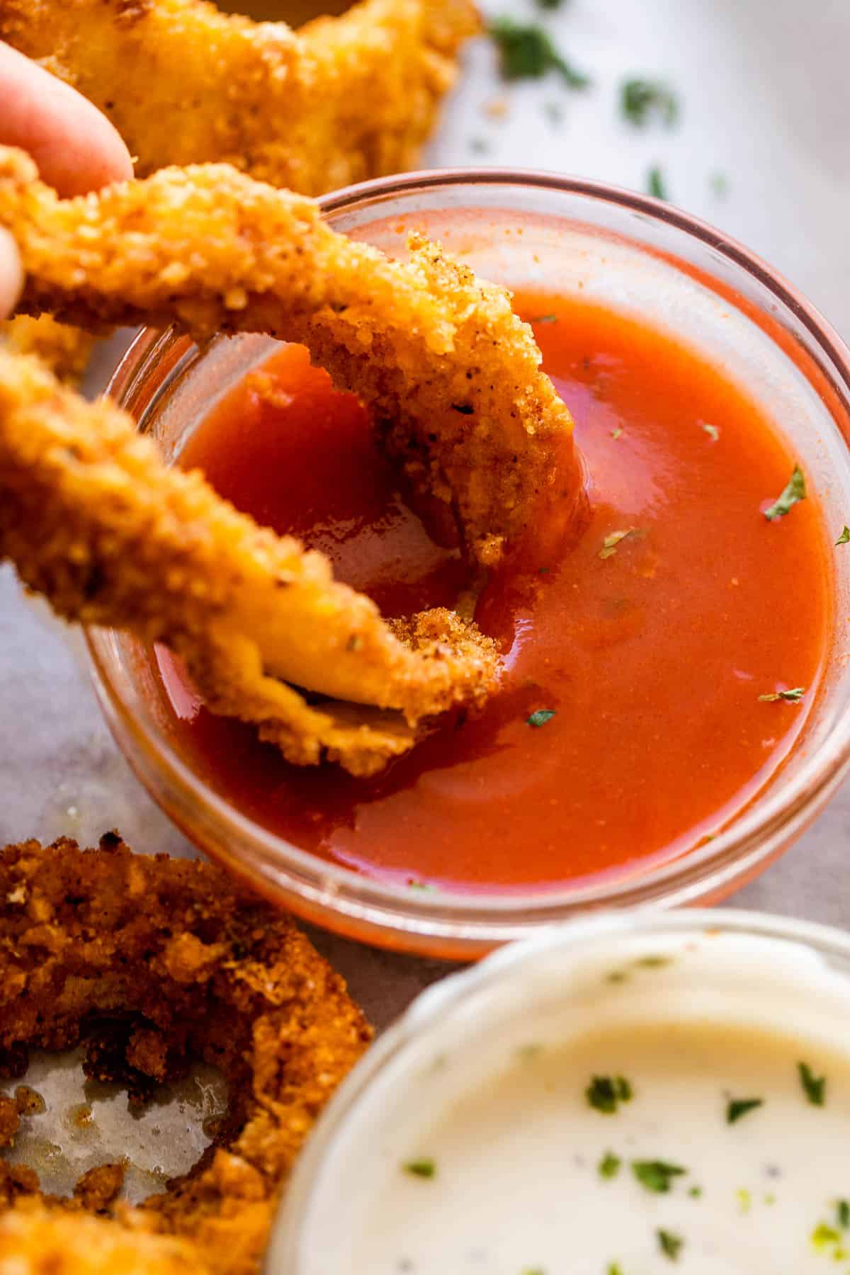 Dipping a homemade onion ring in barbecue sauce.