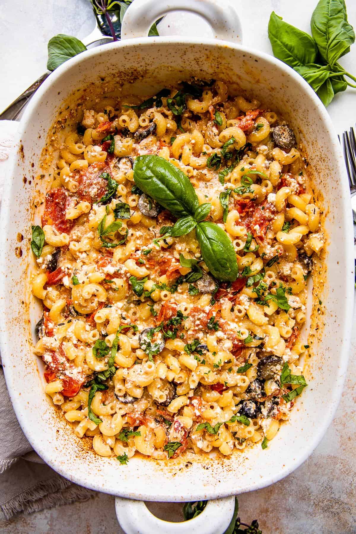 overhead shot of baked feta pasta in a casserole dish and garnished with fresh basil